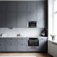 a kitchen with gray cabinets and white counter tops