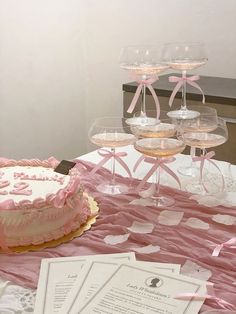 a pink cake sitting on top of a table next to wine glasses and menus