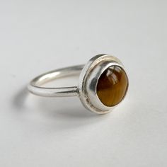 I carefully hand cut, form, file, and finish solid .925 sterling silver into striking and minimal ring. A round 10mm tiger's eye cabochon stone is lovingly bezel set into the band. I can also use other stones if you like - let me know and we can work it out. This piece is completely hand made and truly one of a kind. Every ring is made to order to the above specifications. I invest great care in every piece. You can expect your ring to closely resemble the one pictured, However, all pieces are m Silver Crown Ring, Peace Necklace, Minimal Ring, Jewelry Design Inspiration, Silver Crown, Hammered Sterling Silver, Cabochon Ring, Black Onyx Ring, Eye Ring