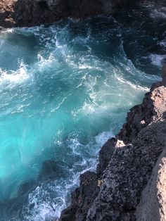 the water is blue and green as it comes out of the rocks into the ocean