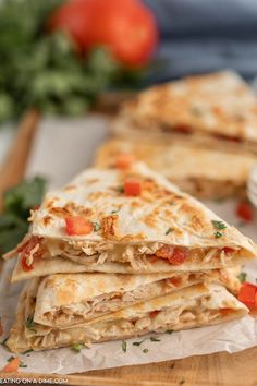 three quesadillas stacked on top of each other with tomatoes in the background