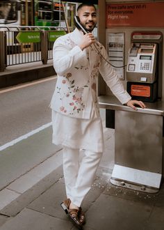 a man standing next to an atm machine on the side of the street with his hand in his pocket