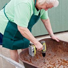 an older woman is using a drill to fix a rusted metal tub with a screwdriver