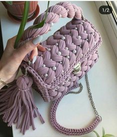 a woman is holding a purple purse with tassels and beads on the handle