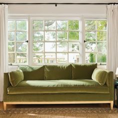 a green couch sitting in front of a window