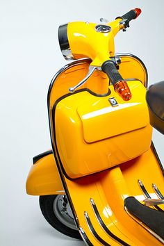 a yellow motor scooter parked on top of a white floor