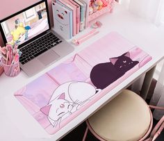 a laptop computer sitting on top of a desk next to a cat mouse pad and pink chair