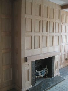 an empty room with a fireplace and wooden paneling