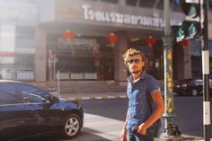 a man is walking down the street in front of a building with cars parked on it