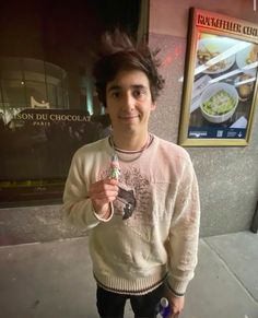 a young man standing on the sidewalk with food in his hand