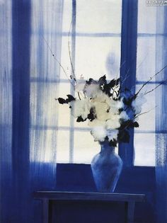 a blue vase with white flowers on a table in front of a curtained window