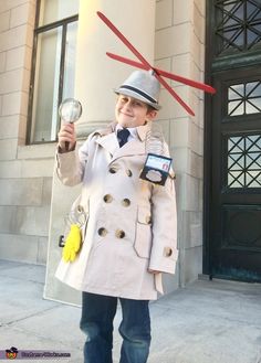 a boy dressed as a doctor who is holding a magnifying glass in front of a building