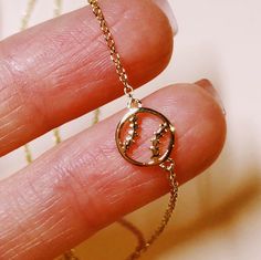 a hand holding a tiny gold necklace on it's finger with the word love spelled in small letters