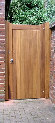 an open wooden gate on the side of a brick building