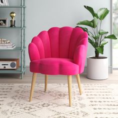 a pink chair sitting on top of a white rug next to a potted plant