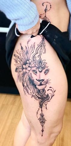 a woman's thigh with tattoos on it and a lion tattoo on the side