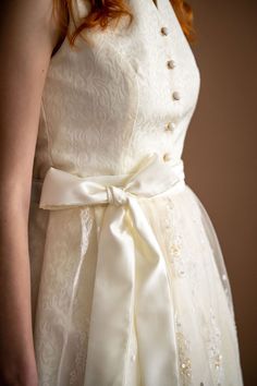 This breathtaking ivory bridal dirndl is a true masterpiece. Crafted from luxurious Jacquard satin fabric, it exudes elegance and sophistication. The bodice is a tailored fit with high collar and gentle v-neckline. The real showstopper, however, is the beaded and embroidered lace apron that adorns the front of the skirt. This intricately detailed apron with delicate lace and beading that shimmers and sparkles in the light. The pearlescent buttons add a touch of glamour to the design. Overall, this ivory bridal dirndl is a work of art that is sure to make any bride feel like royalty on her special day. Ivory jacquard satin medium-length bridal dirndl Pleated skirt length is 26" from the waist to the hemline High collar neckline with gold and pearlescent buttons 2 Skirt pockets Ivory Beaded Dirndl Lace, Bridal Dirndl, Wedding Dirndl, Lace Apron, Skirt Pockets, Ivory Bridal, Ivory Wedding, Plus Size Wedding, Beaded Lace