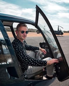 a man sitting in the driver seat of a small plane with another helicopter behind him