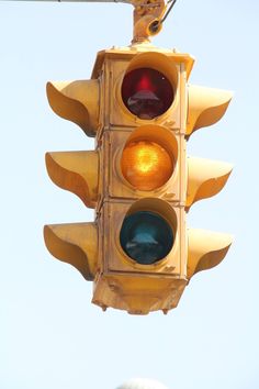 a traffic light hanging from the side of a pole with a blue sky in the background