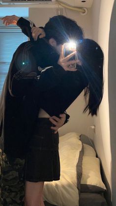 two people standing in front of a bed with their arms around each other and one person taking a selfie