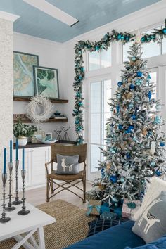 a living room decorated for christmas with blue and silver decorations on the tree, couches, coffee table and fireplace