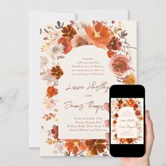 a person holding up a phone next to a wedding card with an orange and white floral design