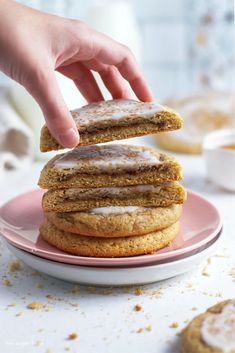 a stack of cookies with icing on top of each one sitting on a pink plate