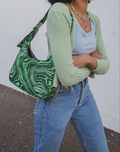 a woman walking down the street carrying a green purse