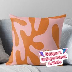 an orange and pink pillow with the words support independent artists in white lettering on it