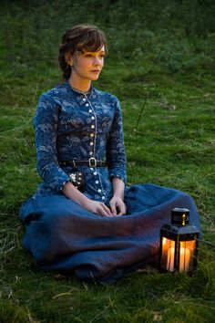 a woman sitting on the ground next to a lantern