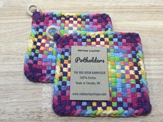 two colorful crocheted potholders sitting on top of a wooden table next to a tag