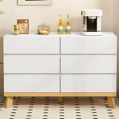 there is a white dresser with two bottles on it and a coffee maker next to it