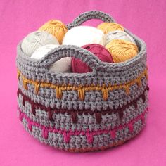 a crocheted basket with balls of yarn in it on a pink background,