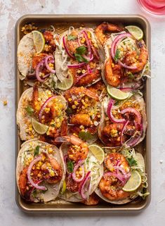 a tray filled with shrimp tacos and lime wedges