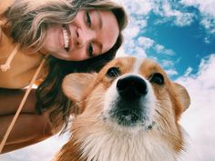 a woman is petting a brown and white dog in front of a blue sky