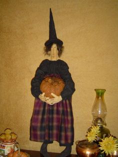 a statue of a witch holding a pumpkin in front of other items on a table