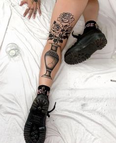 a woman's legs with tattoos and flowers on them, sitting on a bed