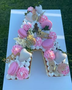 a letter shaped cake with pink frosting and gold decorations