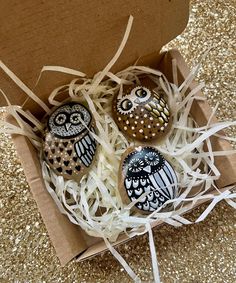 three decorated owl eggs in a cardboard box