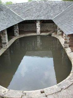 a small pond in the middle of a stone building with two roof tops on each side