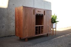 a wooden cabinet sitting on the side of a road next to a potted plant