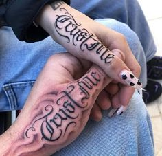 two people with tattoos on their hands holding one another's hand and the other has writing on it