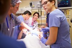 three doctors are looking at a patient in the hospital