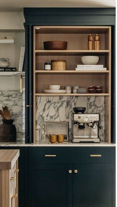 a kitchen with black cabinets and marble counter tops, gold pulls on the cupboards