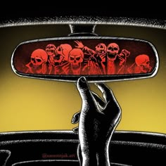 a hand holding up a car mirror with skulls on it