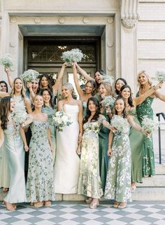 a group of women standing next to each other in front of a building holding bouquets