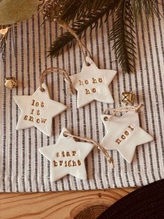 three white ceramic stars with words on them sitting next to a christmas tree and decorations