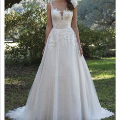 a woman wearing a wedding dress standing in the grass