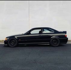 a black car parked in front of a white wall