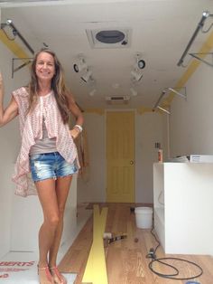 a woman standing on top of a wooden floor next to a white refrigerator freezer